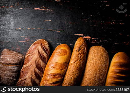A variety of delicious bread on the table. Against a dark background. High quality photo. A variety of delicious bread on the table.