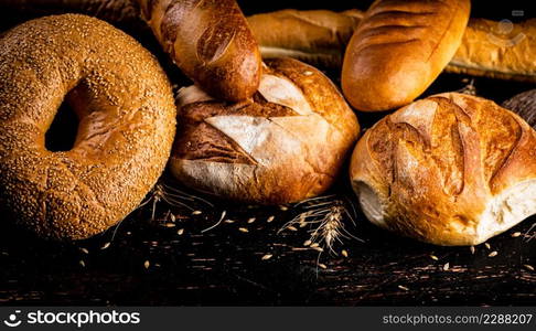 A variety of delicious bread on the table. Against a dark background. High quality photo. A variety of delicious bread on the table.