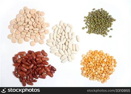 A variety of different dried beans. White beans in the centre with, clockwise from top left, thermos beans, mung beans, split peas and red kidney beans.