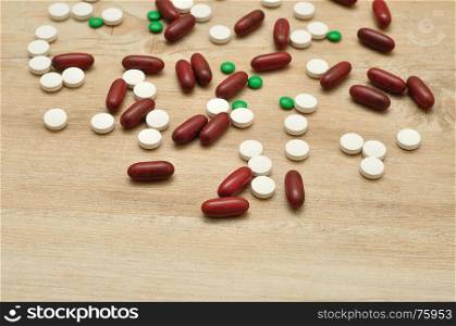 A variety of different pills on a wooden background