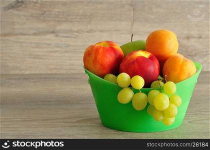 A variety of fruit in a green plastic bucket