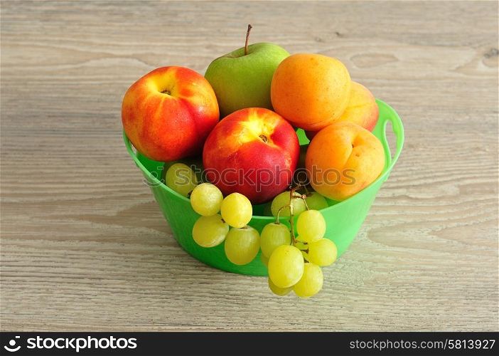 A variety of fruit in a green plastic bucket