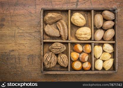 a variety of nuts (walnut, pecan, hazelnut, Brazilian and almond) in a rustic wooden box against grunge wood surface with a copy space