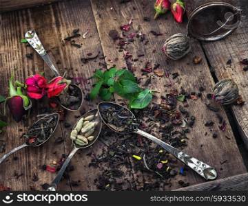 A variety of types of tea. Dry brew tea in vintage and spoons on wooden background