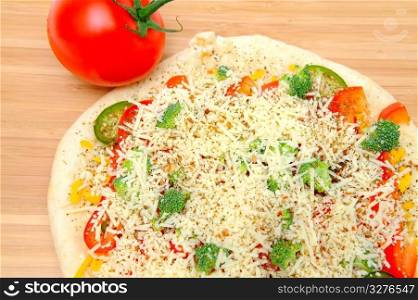 A veggie pizza ready to go into the oven topped with sharp cheddar and asiago cheese, fresh tomatoes, red bell pepper, mild jalapeno chilie, broccoli and dried herbs. Vegtable Pizza For One