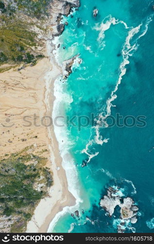 A vertical overhead shot of the beautiful shoreline of the sea with blue clean water and sandy beach. Vertical overhead shot of the beautiful shoreline of the sea with blue clean water and sandy beach