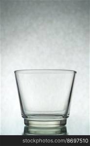 A vertical shot of an empty glass on a grey background. Vertical shot of an empty glass on a grey background