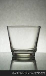 A vertical shot of an empty glass on a grey background. Vertical shot of an empty glass on a grey background