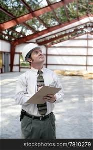 A vertical view of a construction inspector looking at a steel frame building. Room for text.