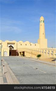 A vertical view of part of Qatar&acute;s State Mosque, showing an entrance stairway, the minaret and part of the outside of the prayer hall.