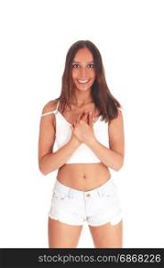 A very happy young woman standing from the front in shorts andwhite top with her hands on her chest, isolated for white background