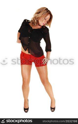 A very pretty and young woman standing in red shorts and black blouseand heels for white background in the studio.
