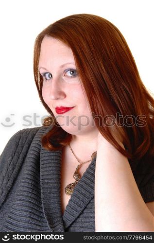 A very pretty young woman in a portrait shot, wearing a gray dress andred brunette hair, looking into the camera for white background.