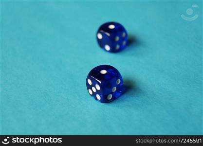 A vibrant monochromatic macro with depth of field about two blue glass gambling dice with two unlucky number one on blue background.