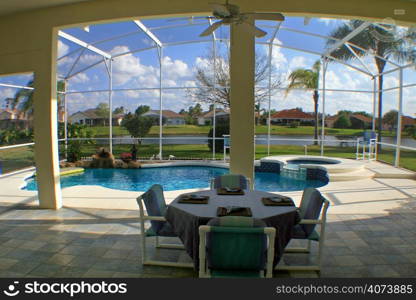 A view from a lanai of a pool, spa and lake.