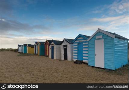 a view from the front of a line of colourful beach huts, at Southwold, Suffolk
