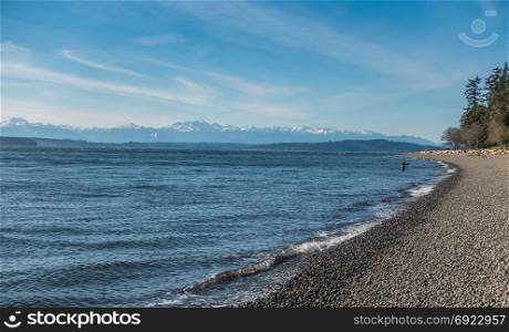 A view of a fisherman and the Olympic Mountains from Lincoln Park in West Seattle, Washington.