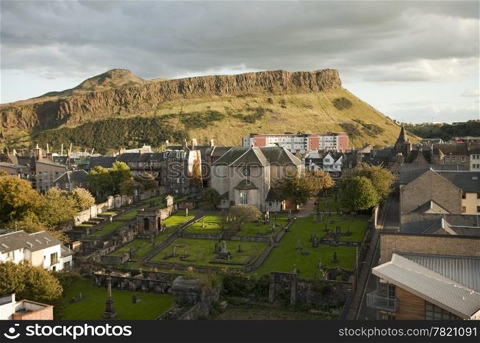 A view of Edinburgh from Calton Hill looking towards the Salisbury Crags in Holyrood Park. At the bottom is one of Edinburgh&rsquo;s ancient graveyards located next to Canongate Kirk.