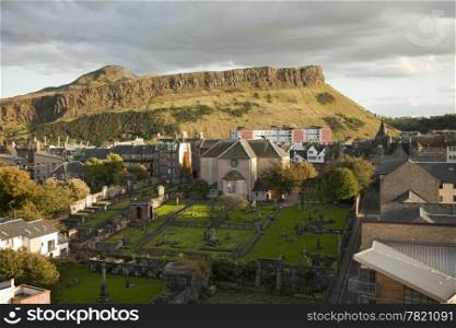 A view of Edinburgh from Calton Hill looking towards the Salisbury Crags in Holyrood Park. At the bottom is one of Edinburgh&rsquo;s ancient graveyards located next to Canongate Kirk.
