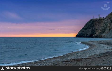 A view of La Chucha Beach and the lighthouse of Cabo Sacratif in Andalusia at asunset