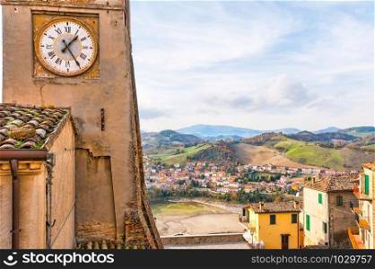 A view of the clock tower of Sassocorvaro, with the little town of Mercatale and the mountains in the background