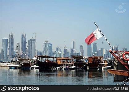 A view of the dhow harbour in Doha, Qatar, with the high-rise development across Doha Bay, a fusion of tradition and modernity which the Qataris are keen to develop. The Qatari national flag is on the right.