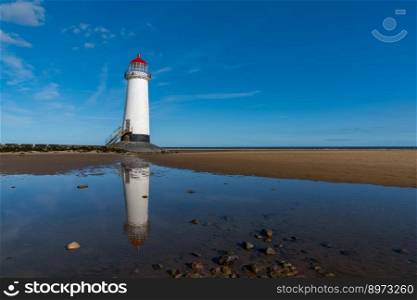 A view of the Point of Ayr Lighthouse and Talacre Beach in northern Wales with reflections in a tidal pool