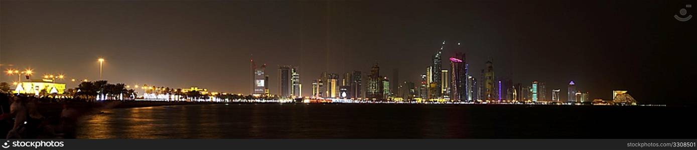A view of the the skyline of Doha lit up for National Day, 2009, just ahead of the firework display, logos removed. Part of the crowd can be seen on the left, blurred by the long exposure.