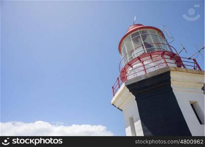 A view of the top of a lighthouse set against a blue sky.