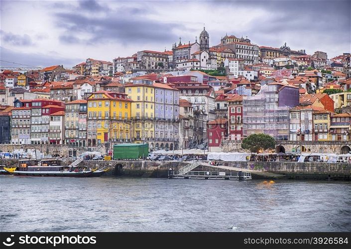 A view of the waterfront promenade on the Douro River with the city of Porto in Portugal rising up on the hills behind.