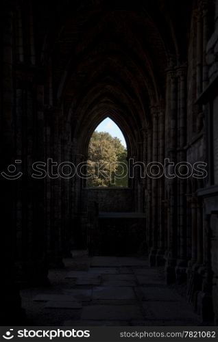 A view through the ruins of Holyrood Abbey towards a window framed in the gothic arch. This is a landmark building attached to Holyrood House in Edinburgh, Scotland.
