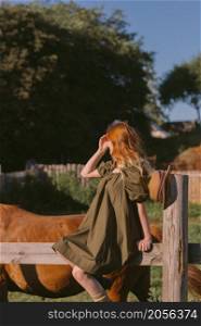 A village pastoral with a red-haired young girl.. A red-haired girl in a green rustic dress rejoices in the sun 3256.