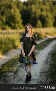 A village red-haired girl walks along a rural road in summer.. Portrait of a village girl on a rural road 3291.