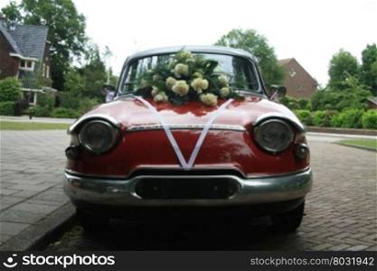 A vintage 1962 French car, decorated with a white satin ribbon and an bouquet of white roses