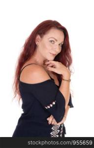 A waist up picture of a pretty woman with long red hair holding one hand under her chin smiling into the camera, isolated for whitebackground