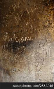A wall of a temple in india that has had visitors scratch their names into the stone surface.