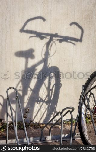 a wall shadow of mountain bicycle parked in racks - a commuting concept