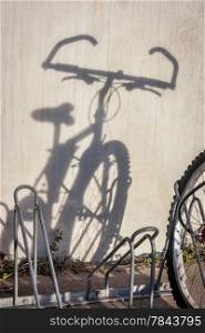a wall shadow of mountain bicycle parked in racks - a commuting concept