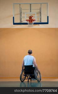 a war invalid in a wheelchair train with a ball at a basketball club in training with professional sports equipment for the disabled. the concept of sport for people with disabilities. High quality photo. a war invalid in a wheelchair trains with a ball at a basketball club in training with professional sports equipment for the disabled. the concept of sport for people with disabilities