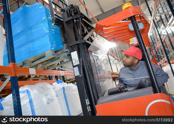 a warehouse worker driving forklift