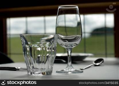 A water glass, and a wine glass, on a table in a cafe