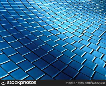 A wave effect created by light and shadow on the tile of a drained pool.