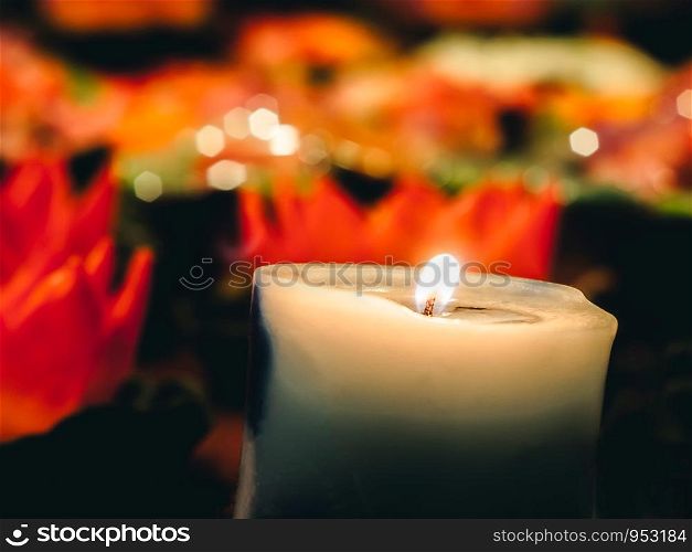 A wax or tallow with a central wick that is lit to produce light as it burns. Many burning candles with shallow depth of field, Black hexagonal bokeh background