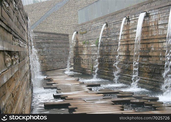 A way to a wall with water outflows over. 