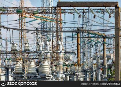 A web of electrical wires and high-voltage dielectric insulators on the metal masts of a substation on a light day.. A fragment of an electrical substation with many wires and dielectric insulators.
