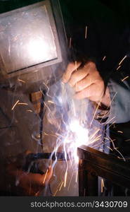 A welder using a mig torch to attach two pieces of metal.