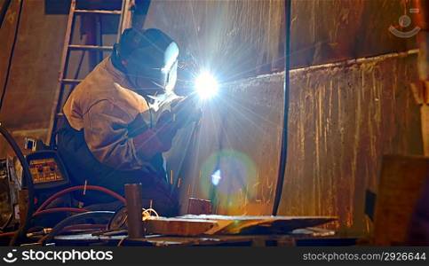 a welder working at shipyard building a ship