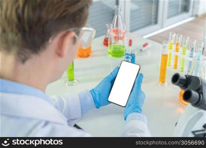 A western scientist man holding blank space smartphone, working on test tube to analysis and develop vaccine of covid-19 virus in lab or laboratory in technology medical. Experimental science.