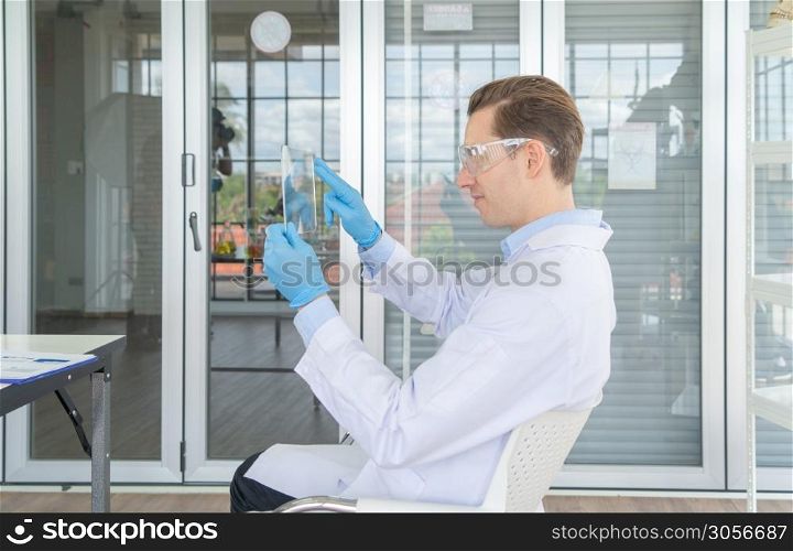 A western scientist man using hologram tablet with copy space to analysis and develop vaccine of covid-19 virus in lab or laboratory in technology medical, chemistry, healthcare, research. Experiment.