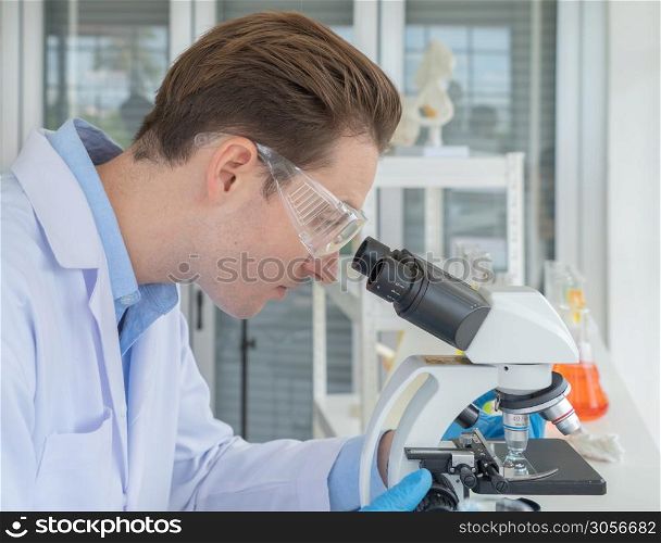 A western scientist man working on test tube to analysis and develop vaccine of covid-19 virus in lab or laboratory in technology medical, chemistry, healthcare, research. Experimental science.